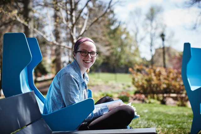 Student in a blue chair on the Pius Library patio 